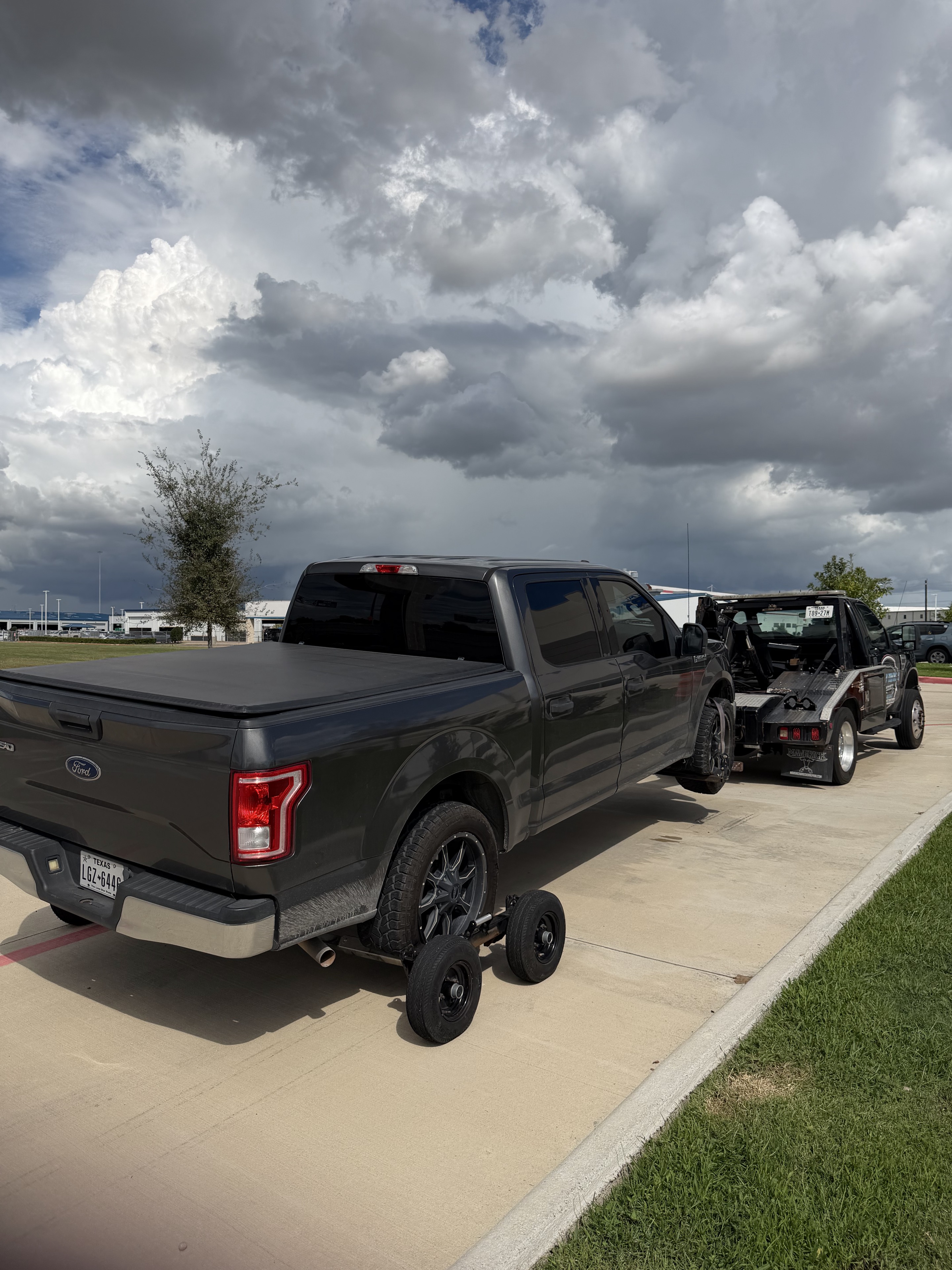 Rear dollies supporting a gray Ford F-150 during a tow
