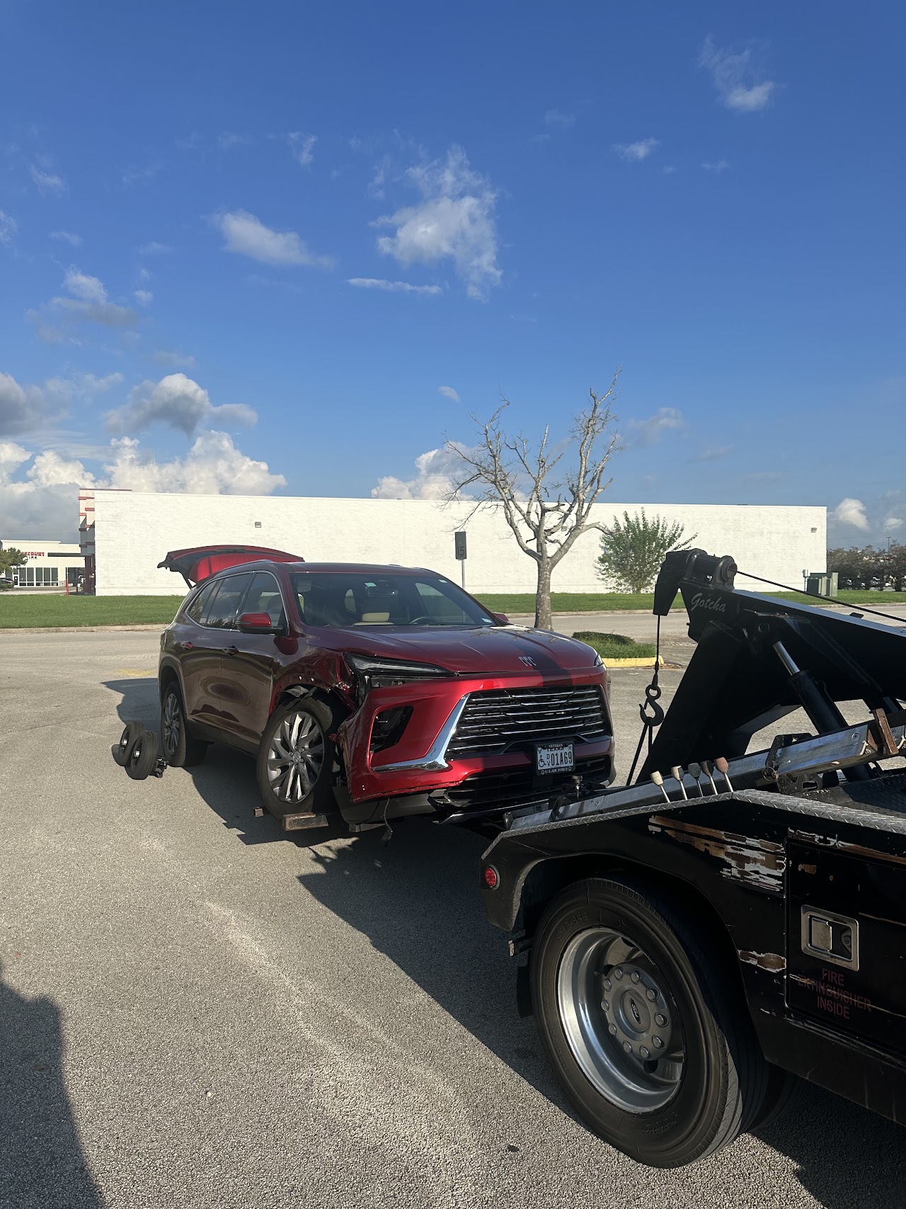 Red SUV with visible front-side damage supported by a wheel-lift and rear dollies