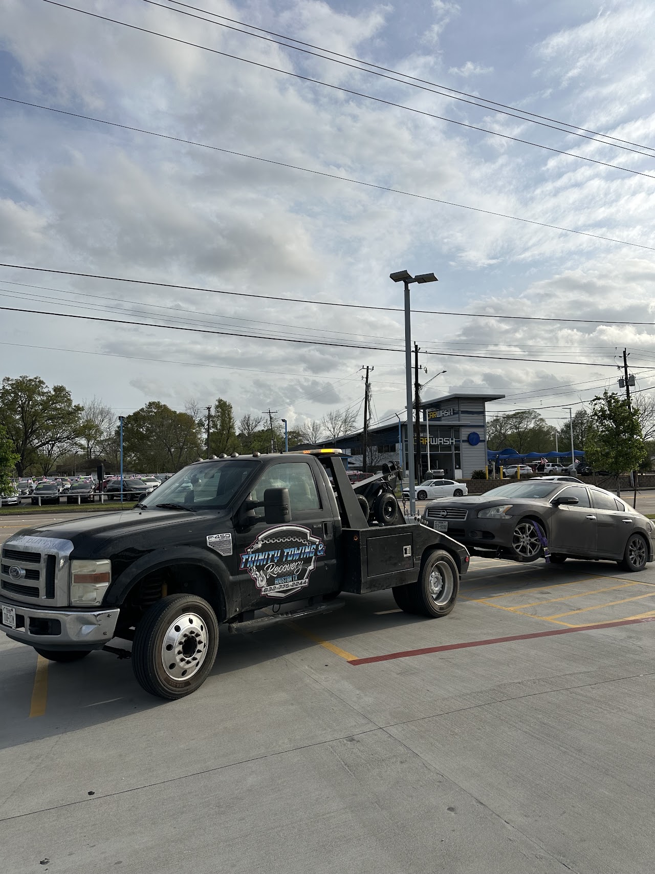 Our tow truck with a gray Nissan sedan supported at its front wheels
