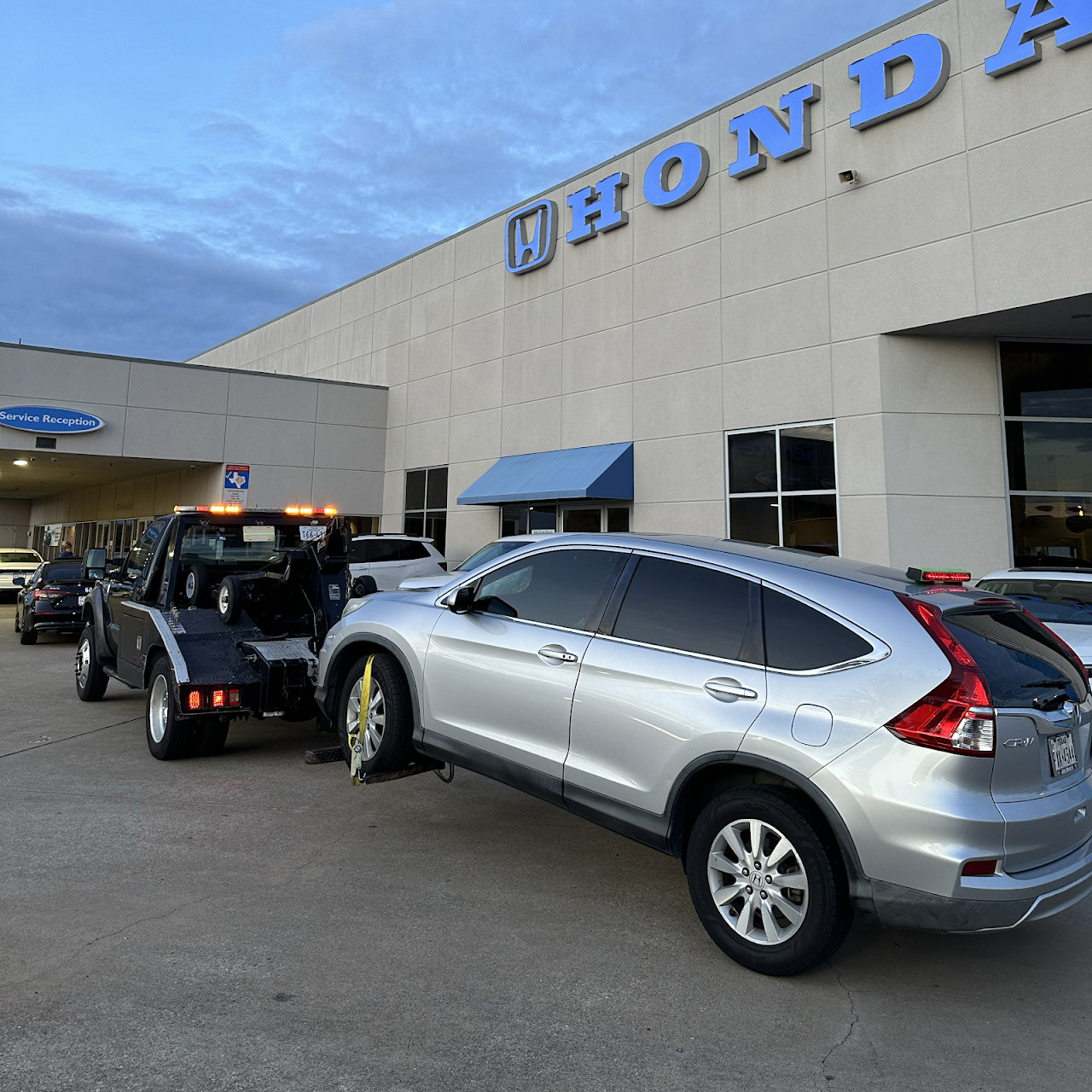 Our tow truck with a silver Honda CR-V outside a Honda service department
