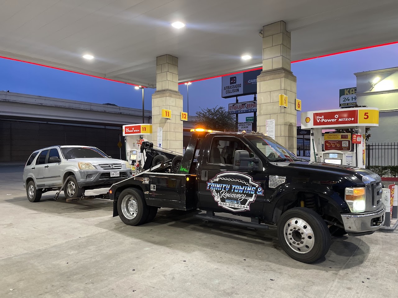 Our tow truck with a white Honda CR-V supported by a front wheel-lift at a gas station